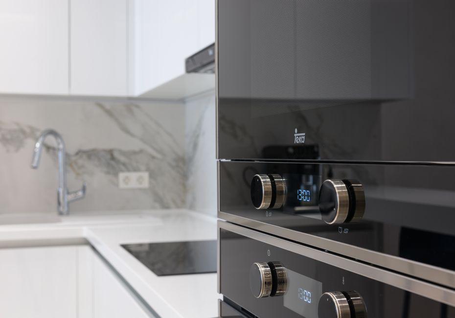 Interior of contemporary kitchen with stainless white surface induction cooker and electronic stove in modern apartment