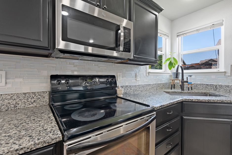 Stylish modern kitchen with stainless steel microwave, stove, and granite countertops.